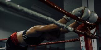 A dedicated female boxer rests in the ring, showcasing strength and perseverance.