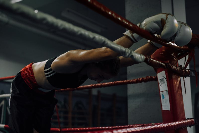 A dedicated female boxer rests in the ring, showcasing strength and perseverance.